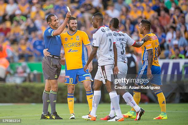 Andre Gignac of Tigres hugs referee Luis Santander as he gives a yellow card to Ismael Sosa during the 2nd round match between Tigres UANL and Atlas...