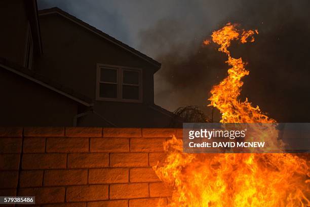 Flames lap at the wall of a home at the Sand Fire on July 23 2016 near Santa Clarita, California. Fueled by temperatures reaching about 108 degrees...