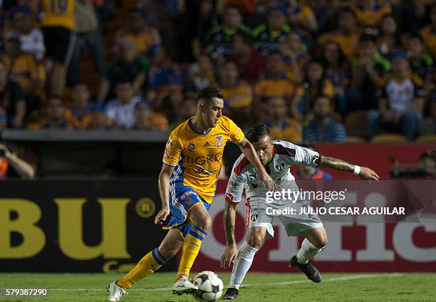 Israel Jimenez of Tigres vies for the ball with Christian Tabo of Atlas during the Mexican Apertura 2016 tournament football match at the...