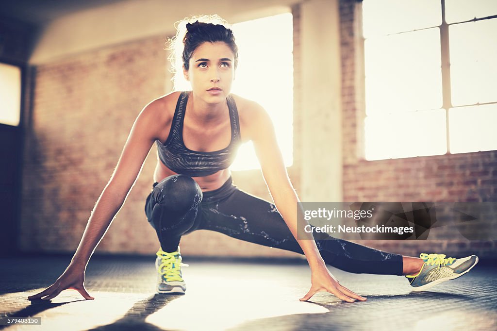 Sporty woman doing stretching exercise before workout in gym