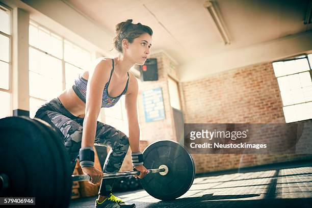 low angle view of determined woman deadlifting with barbell - deadlift stock pictures, royalty-free photos & images