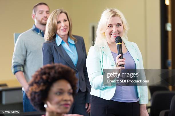 blonde woman holding microphone asks question - câmara municipal edifício do governo local imagens e fotografias de stock