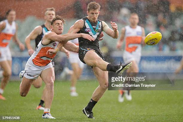 Stephen Coniglio of the Giants tackles Hamish Hartlett of the Power as he kicks the ball during the round 18 AFL match between the Port Adelaide...