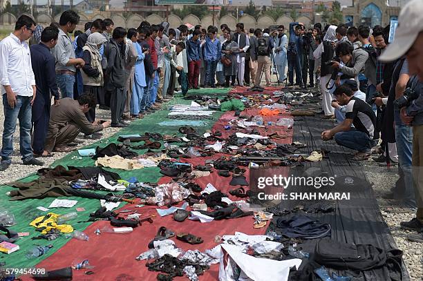 Relatives and friends inspect shoes and other belongings of those who were killed in the twin suicide attack, gathered on the ground at a mosque in...