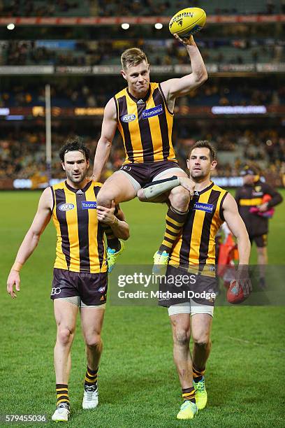 Sam Mitchell of the Hawks is carried off by Jordan Lewis amd Luke Hodge after winning his 300th match during the round 18 AFL match between the...