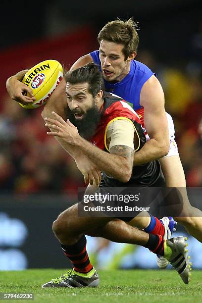 Courtenay Dempsey of the Bombers is tackled by Ryan Bastinac of the Lions during the round 18 AFL match between the Essendon Bombers and the Brisbane...