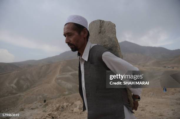An Afghan mourner carries a tombstone ahead of funeral prayers for the 80 people killed in the twin suicide attack, in Kabul on July 24, 2016. Kabul...
