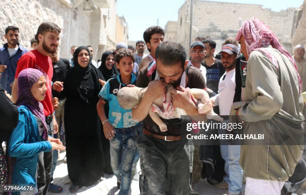 Syrian man holds the body of his child after it was taken from under the rubble of destroyed buildings following a reported air strike on the...