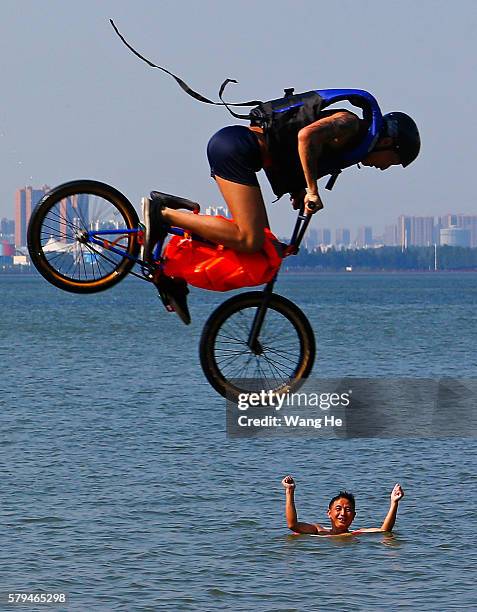 An extreme cycling enthusiast performs a stunt with a bicycle before falling into the East Lake in on July 24, 2016 in Wuhan, Hubei province, China....