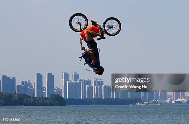 An extreme cycling enthusiast performs a stunt with a bicycle before falling into the East Lake in on July 24, 2016 in Wuhan, Hubei province, China....