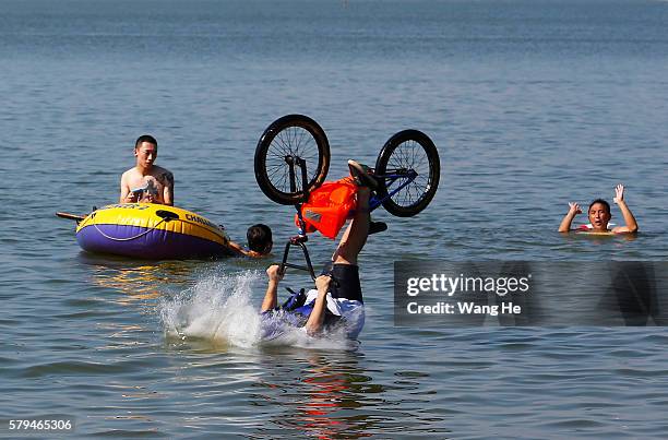 An extreme cycling enthusiast performs a stunt with a bicycle before falling into the East Lake in on July 24, 2016 in Wuhan, Hubei province, China....