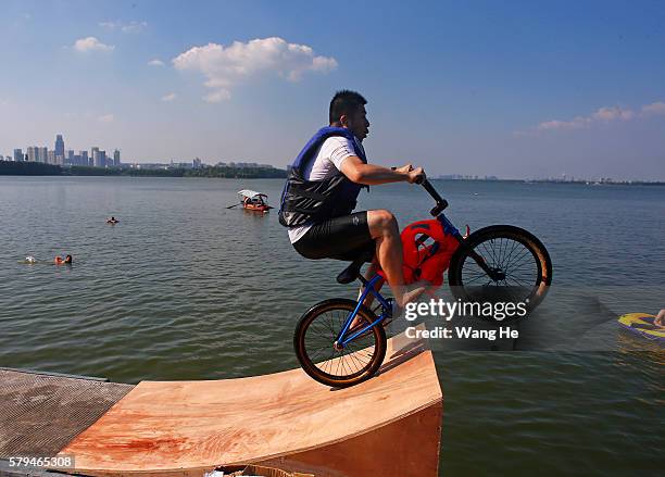 An extreme cycling enthusiast performs a stunt with a bicycle before falling into the East Lake in on July 24, 2016 in Wuhan, Hubei province, China....