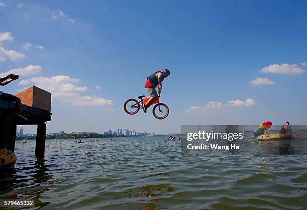 An extreme cycling enthusiast performs a stunt with a bicycle before falling into the East Lake in on July 24, 2016 in Wuhan, Hubei province, China....