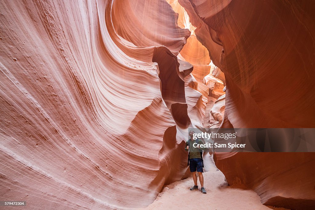 Male tourist hiker and sandstone rock formations, Lower Antelope Canyon, Page, Arizona, USA