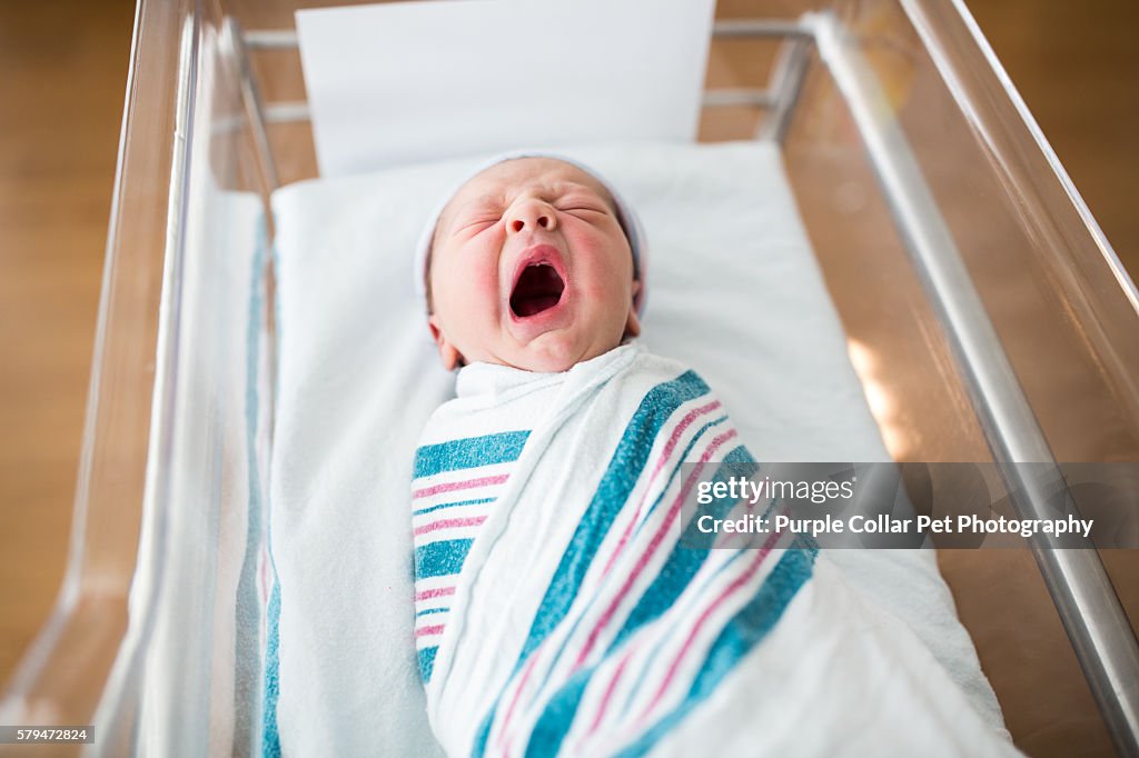 Newborn Infant Yawning in Crib