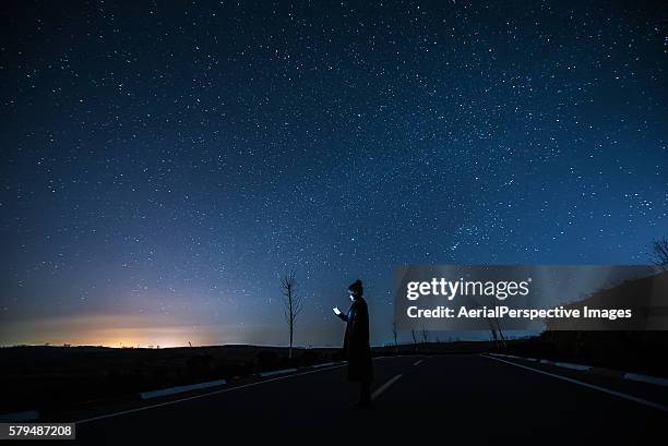 girl using a mobile phone in starry night - woman smartphone nature stockfoto's en -beelden