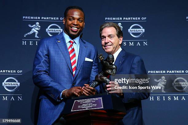 Derrick Henry Running Back University of Alabama and his head coach Nick Saban pose with the Heisman Trophy during a press conference after winning...