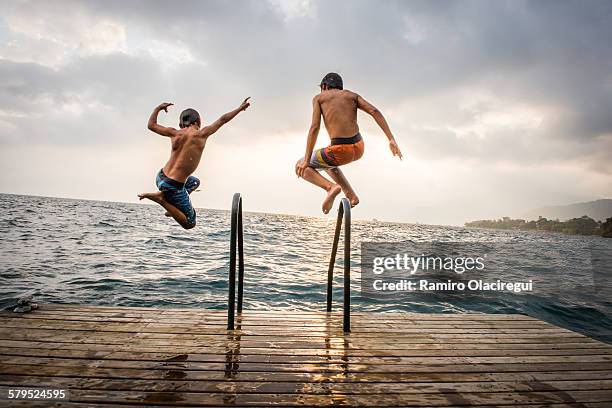 brothers jumping in a lake - lake atitlan 個照片及圖片檔