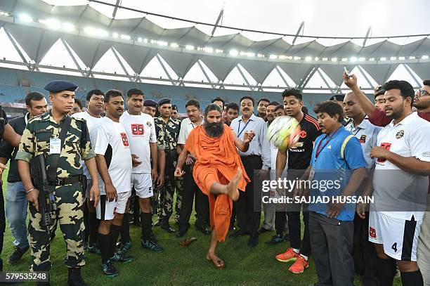 Indian yoga guru Baba Ramdev kicks a football ahead of a charitable football match between Indian Bollywood actors and Indian Parliamentarians in New...