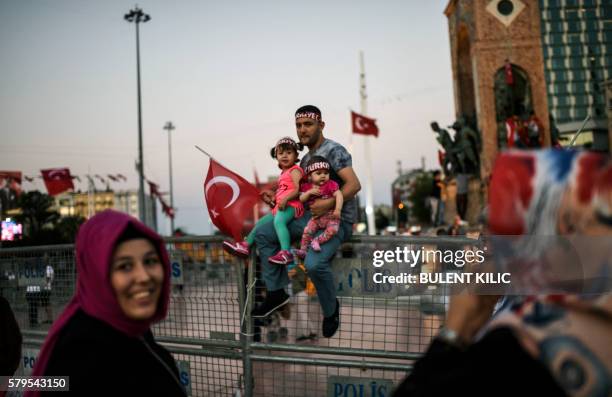Man holds two children and a Turkish flag in Istanbul's Taksim Square on July 24, 2016 during the first cross-party rally to condemn the coup attempt...