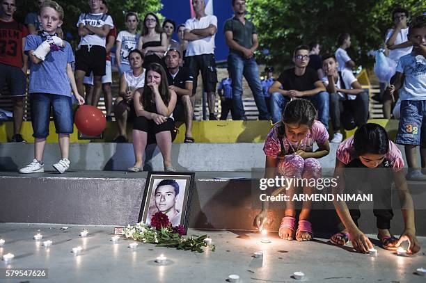 People mourn and lit candles in Pristina on July 24, 2016 next to a picture of Diamant Zabergja, one of the victims that was shot dead at the Olympia...