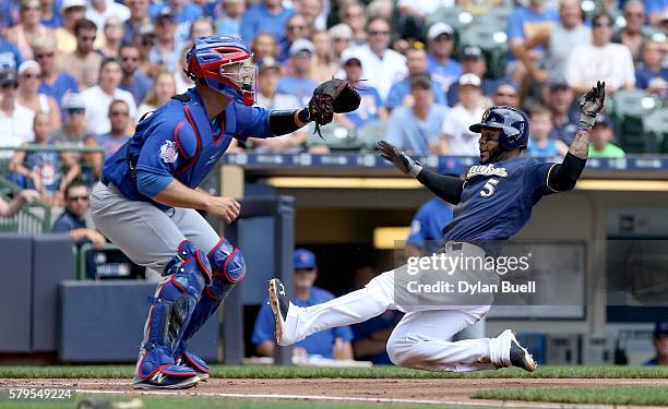 Jonathan Villar of the Milwaukee Brewers slides into home to score against David Ross of the Chicago Cubs in the first inning at Miller Park on July...