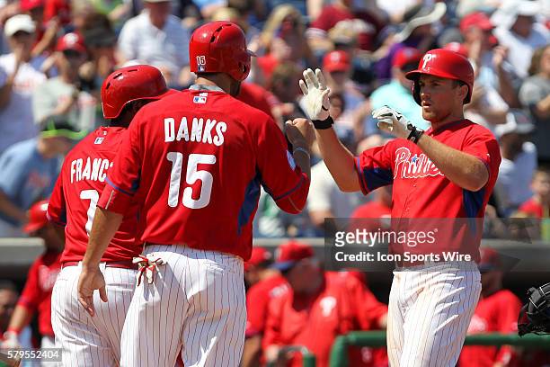 Maikel Franco and Jordan Danks of the Phillies congratulates Cord Phelps after Phelps hit a long home run during the spring training game between the...