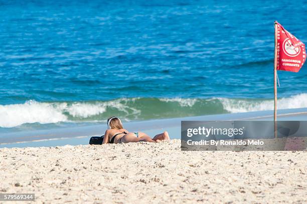 girl sunbathing listening to music with a flag dangerous current. - comprimento fotografías e imágenes de stock