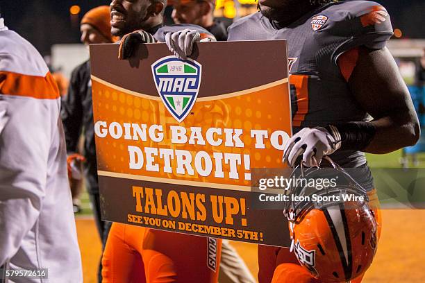 Bowling Green players hold a sign boasting that team is returning to the MAC championship game as they walk off of the field at the conclusion of the...