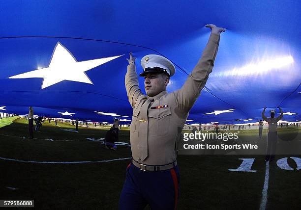 Marines helps hold a big American flag during the national anthem before the start of the Holiday Bowl game played between the Wisconsin Badgers and...
