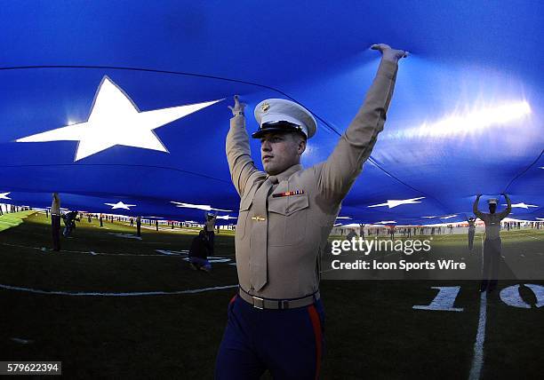 Marine helps hold a big American flag during the national anthem before the start of the Holiday Bowl game played between the Wisconsin Badgers and...