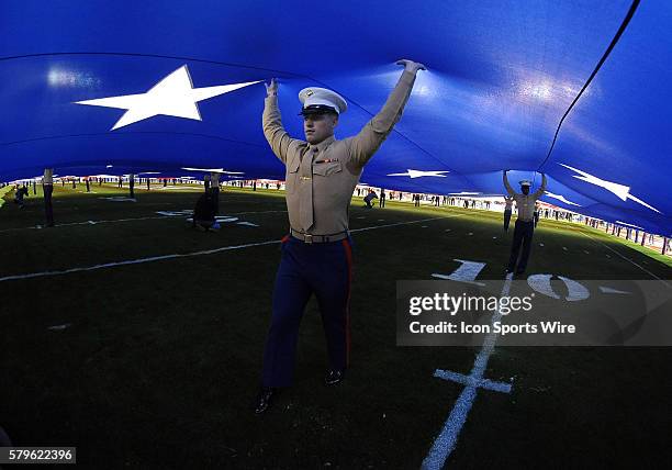 Marine helps hold a big American flag during the national anthem before the start of the Holiday Bowl game played between the Wisconsin Badgers and...