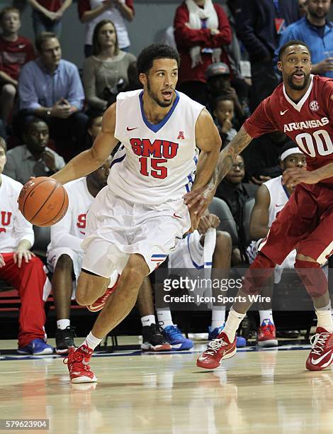 Mustangs center Cannen Cunningham dribbles past Arkansas Razorbacks guard Rashad Madden during the college basketball game between the SMU Mustangs...