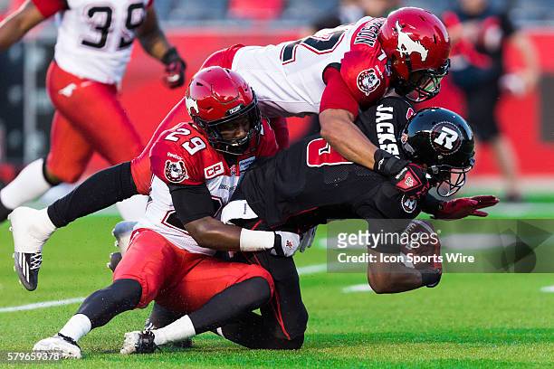 Calgary Stampeders Jamar Wall and Juwan Simpson tackle Ottawa RedBlacks Ernest Jackson during Canadian Football League action between the Calgary...