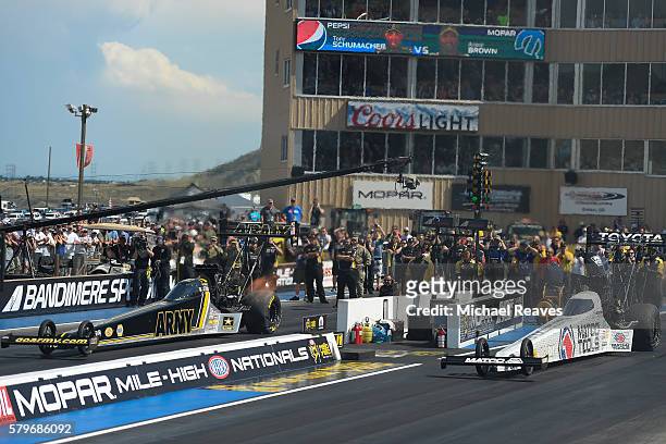Top Fuel drivers Tony Schumacher and Antron Brown head down the track in the finals during day three of the NHRA Mile High Nationals at Bandimere...