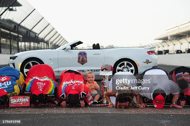 Kyle Busch, driver of the Skittles Toyota, kisses the bricks with his wife, Samantha, and son, Brexton, after winning the NASCAR Sprint Cup Series...