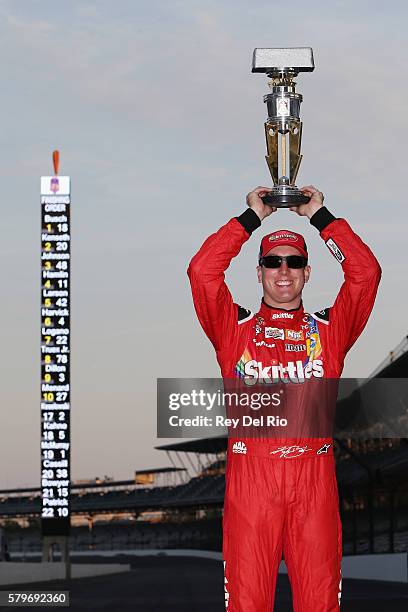 Kyle Busch, driver of the Skittles Toyota, poses after winning the NASCAR Sprint Cup Series Crown Royal Presents the Combat Wounded Coalition 400 at...