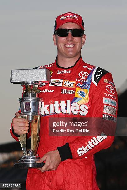 Kyle Busch, driver of the Skittles Toyota, poses after winning the NASCAR Sprint Cup Series Crown Royal Presents the Combat Wounded Coalition 400 at...