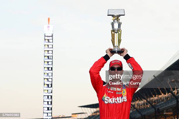 Kyle Busch, driver of the Skittles Toyota, poses after winning the NASCAR Sprint Cup Series Crown Royal Presents the Combat Wounded Coalition 400 at...