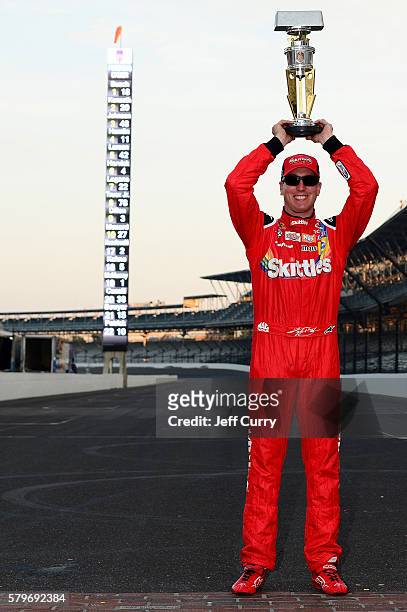 Kyle Busch, driver of the Skittles Toyota, poses after winning the NASCAR Sprint Cup Series Crown Royal Presents the Combat Wounded Coalition 400 at...