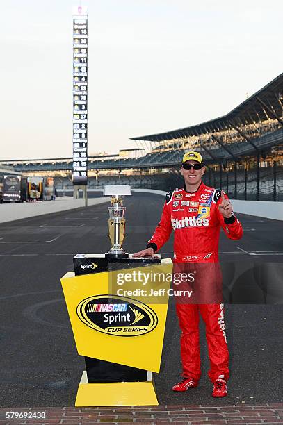 Kyle Busch, driver of the Skittles Toyota, poses after winning the NASCAR Sprint Cup Series Crown Royal Presents the Combat Wounded Coalition 400 at...