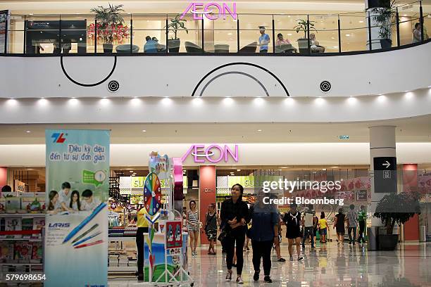 Shoppers walk near signage for Aeon Co. At the retailer's mall in the Long Bien district of Hanoi, Vietnam, on Thursday, July 21, 2016. With a young...
