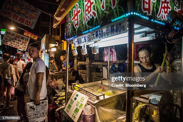 Pedestrians walk past a vendor preparing food at a night market stall in Taipei, Taiwan, on Saturday, July 16, 2016. Taiwan is scheduled to release...