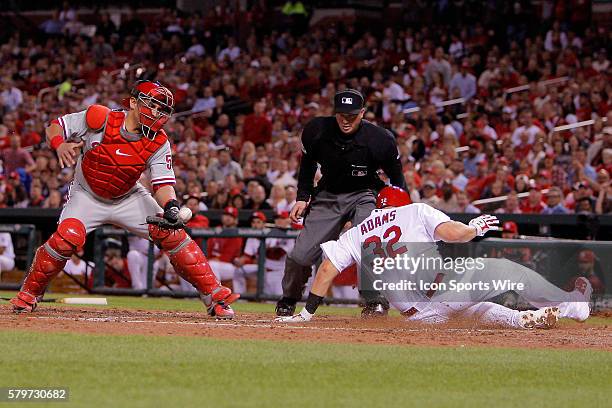 St. Louis Cardinals' Matt Adams safely scores a run as Philadelphia Phillies catcher Carlos Ruiz tries to keep a glove on the ball during the third...