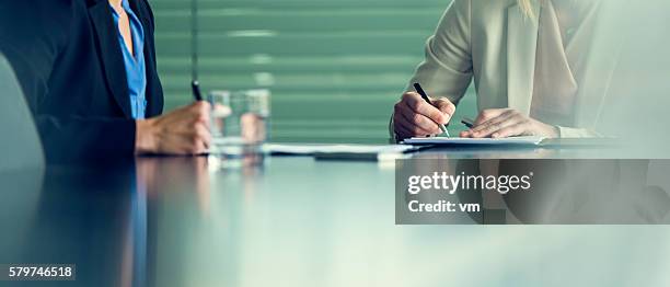 close up of two businesswomen signing contracts at a conference - sign document stock pictures, royalty-free photos & images
