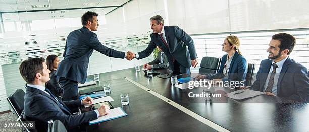 businessmen shake hands over a table - hands-shaking-over-table stock pictures, royalty-free photos & images
