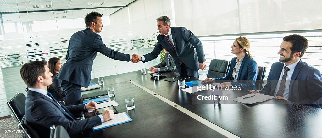 Businessmen shake hands over a table