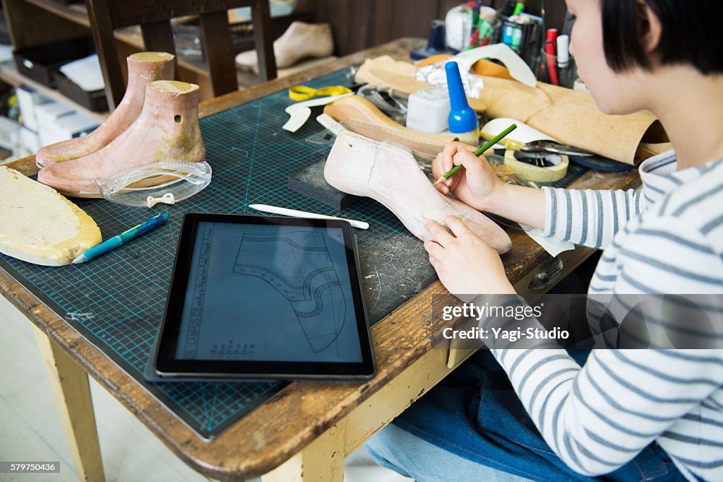 Young female entrepreneur in her shoe making studio