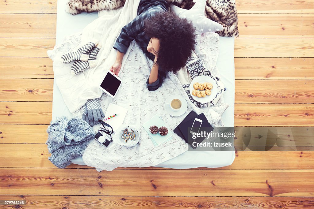 Woman lying on bed and using digital tablet