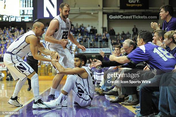 Northwestern Wildcats guard Tre Demps and Northwestern Wildcats center Alex Olah help up Northwestern Wildcats guard Sanjay Lumpkin during a game...